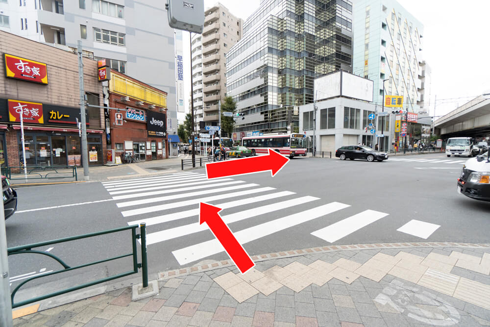 すき家のある交差点に差し掛かったらすき家側に渡り、右手側の横断歩道を渡って直進します。